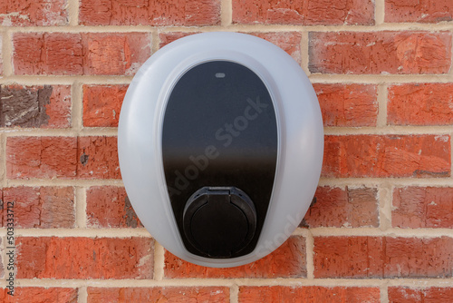 Private electric vehicle charging station fitted to the face of a red brick wall