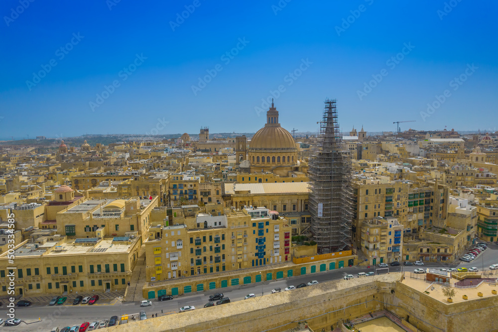 Fototapeta premium Aerial view of Basilica Lady of Mount Carmel church, St. Paul's Cathedral in the old town of Valetta, Malta. Roofs and building with the colorful balconies of Malta capital from above on a sunny day