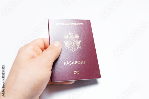 Close-up of male hand holding Moldavian passport of red color, on white.