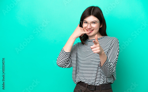 Young Russian woman isolated on green background making phone gesture and pointing front