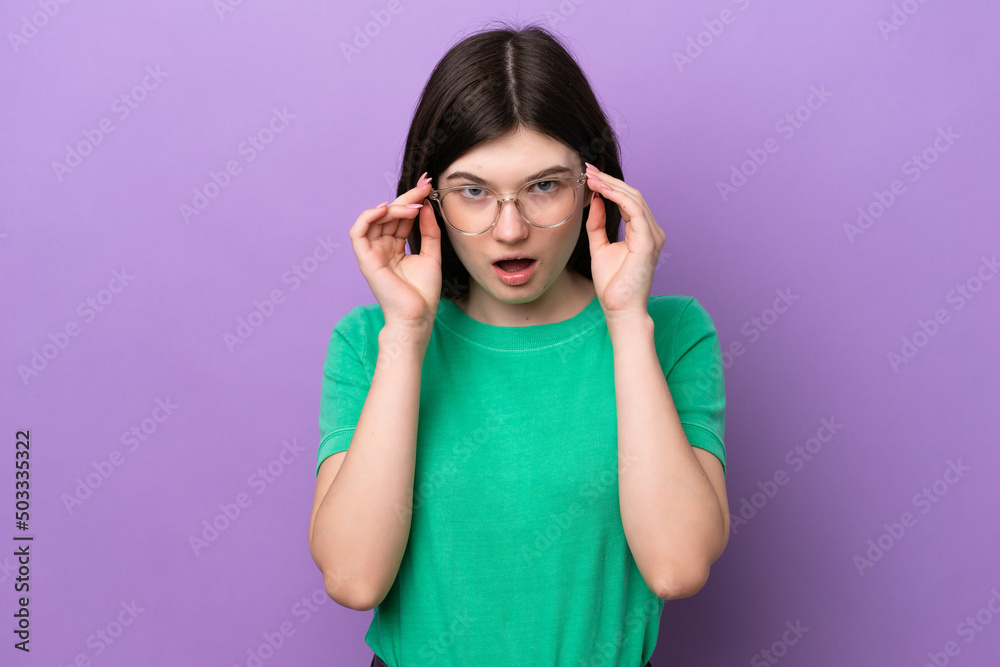 Young pretty Russian woman isolated on purple background With glasses and surprised expression Young pretty Russian woman isolated on purple background With glasses and surprised expression