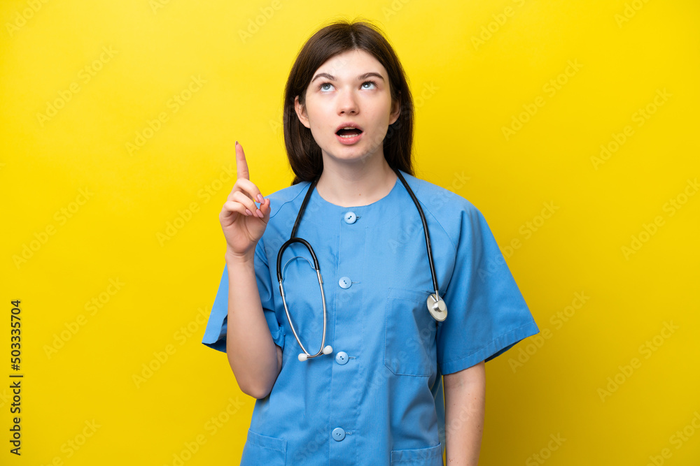 Young surgeon doctor Russian woman isolated on yellow background thinking an idea pointing the finger up Young surgeon doctor Russian woman isolated on yellow background thinking an idea pointing the finger up