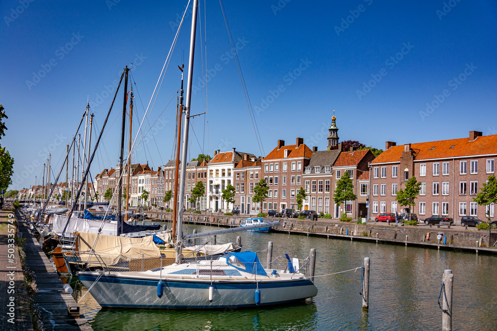 Beautiful perspective view on a water canal with boats and facade buildings in line on a sunny summer day