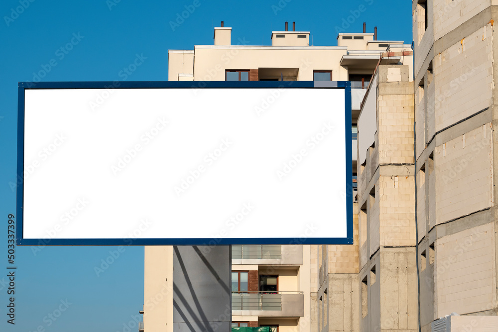 Blank white advertising billboard in front of the building under construction