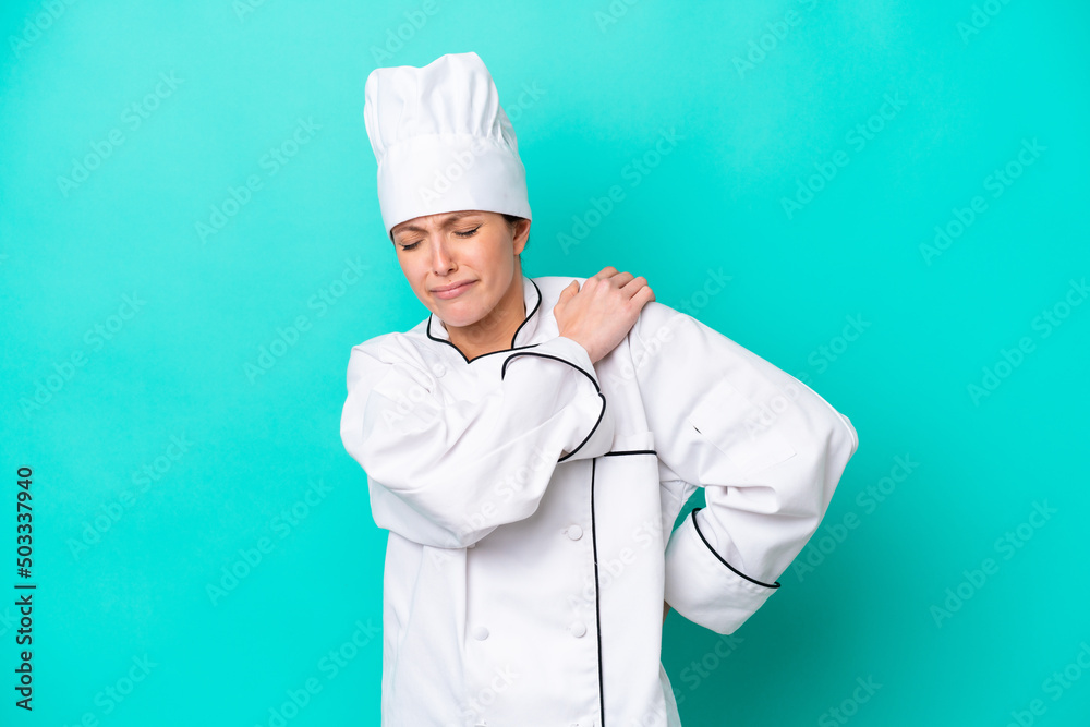 Young caucasian chef woman isolated on blue background suffering from pain in shoulder for having made an effort Young caucasian chef woman isolated on blue background suffering from pain in shoulder for having made an effort