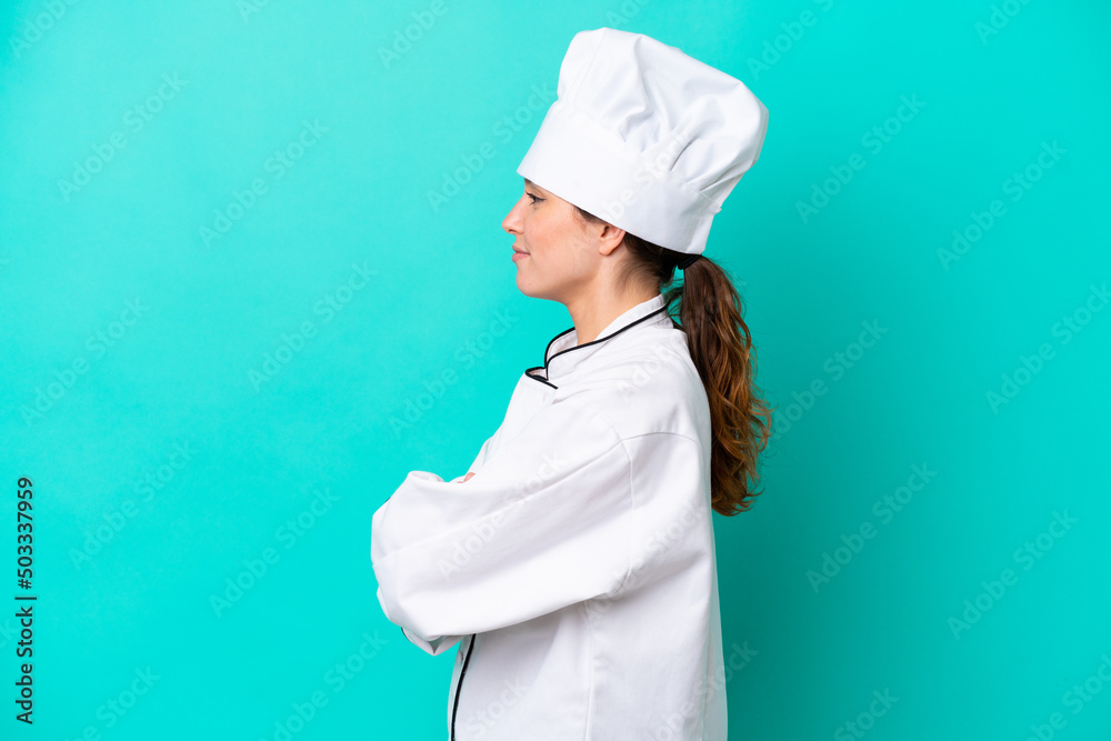 Young caucasian chef woman isolated on blue background in lateral position Young caucasian chef woman isolated on blue background in lateral position