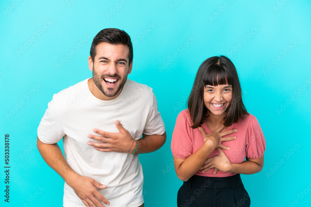 Young couple isolated on blue background smiling a lot while putting hands on chest