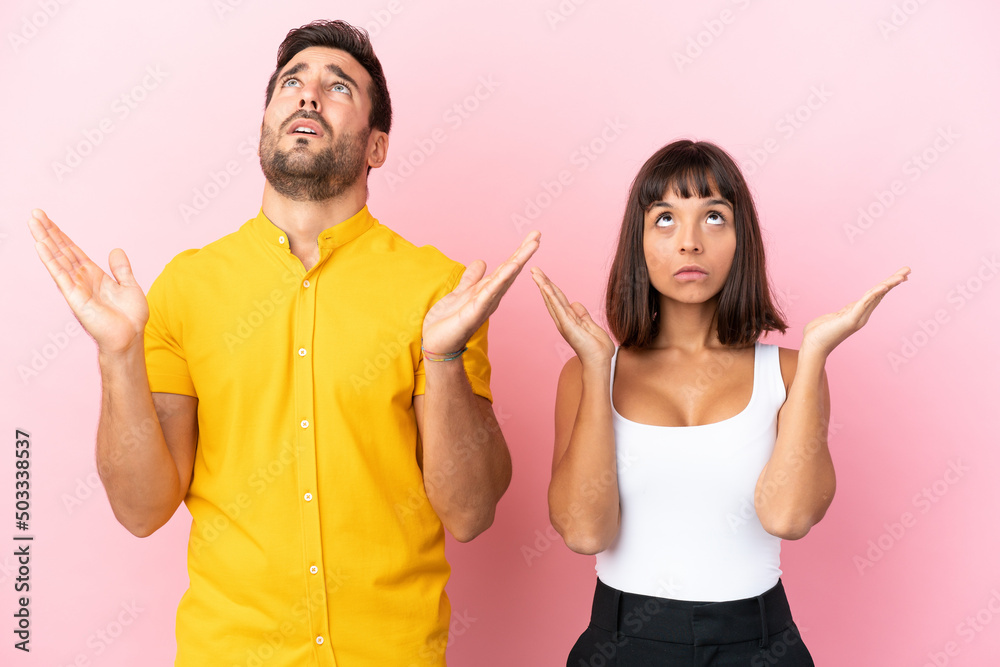 Young couple isolated on pink background frustrated by a bad situation Young couple isolated on pink background frustrated by a bad situation