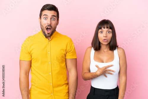 Young couple isolated on pink background with surprise and shocked facial expression