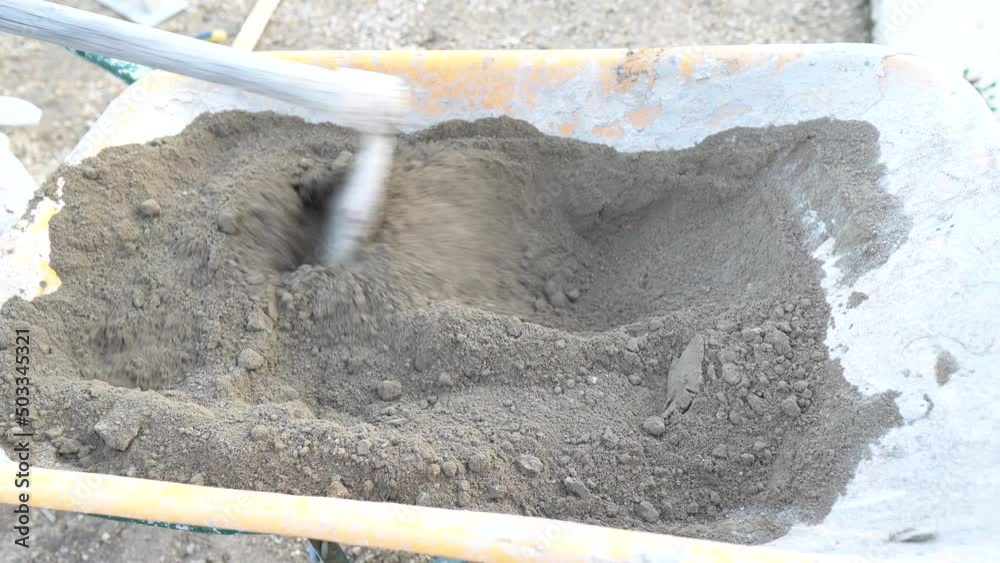 Removiendo arena y cemento en una carretilla para fraguar cemento para una reparación