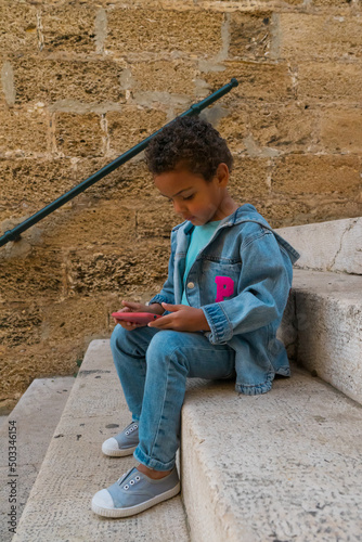 Black boy playing online on cell phone, surfing the internet. New generation addicted to the concept of gadgets. African American boy