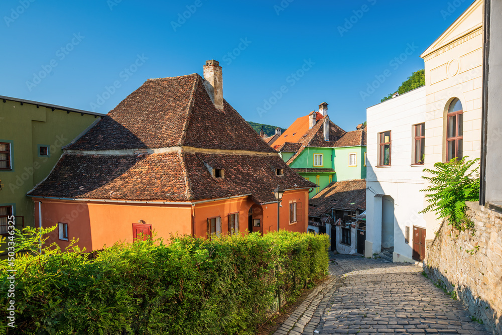 Stone paved medieval streets with colorful houses in Sighisoara, Transylvania region, Romania.