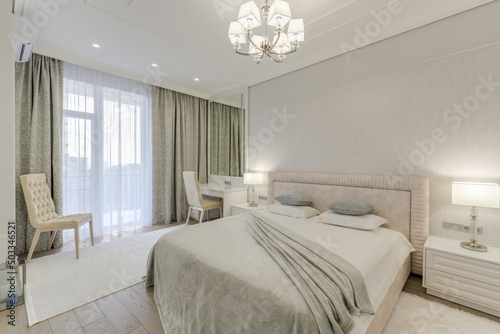 Large grey bedroom with decorated bed and bright furniture in a modern style with lights on