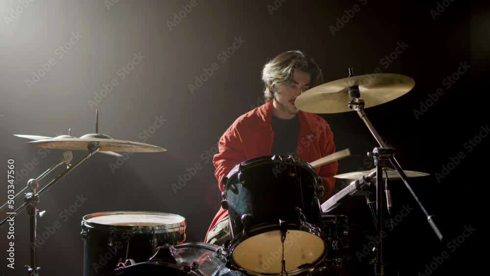 Young male drummer playing drums at music studio while rehearsing alone. Musician performing on percussion instruments. Music, leisure concept