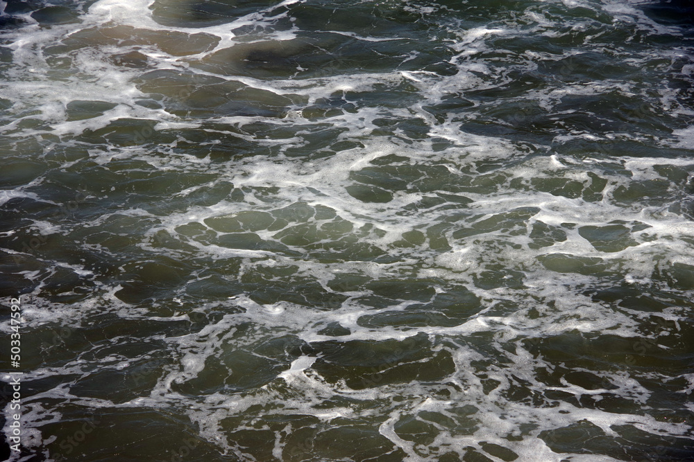 Moving and foaming ocean water surface near the beach Moving and foaming ocean water surface near the beach