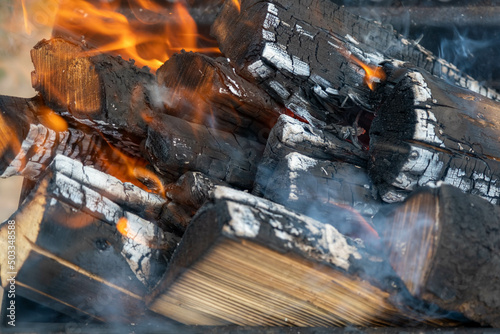 Close up of brightly burning wooden logs with yellow hot flames of fire