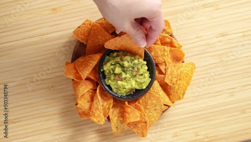 4k video, Eating Traditional Mexican food. A hand taking cooked nachos served with meat and vegetables, tomato soup with cilantro, guacamole top view from wooden tray. Eating cheese Potato Chips