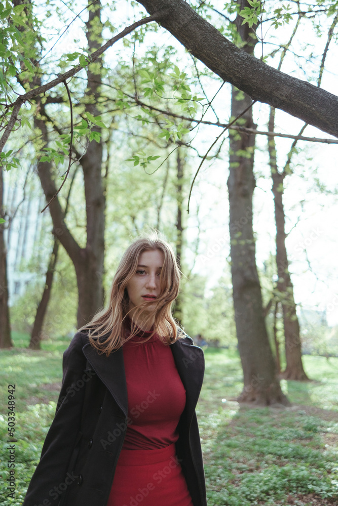 a girl with blonde hair in red golf and a skirt walks through the spring forest a girl with blonde hair in red golf and a skirt walks through the spring forest
