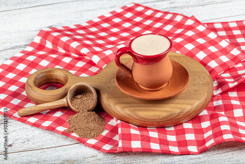 Traditional Turkish Dibek coffee in coffee cup on wooden table. Turkish dibek coffee grinded in a large stone mortar with the traditional hand beating method.