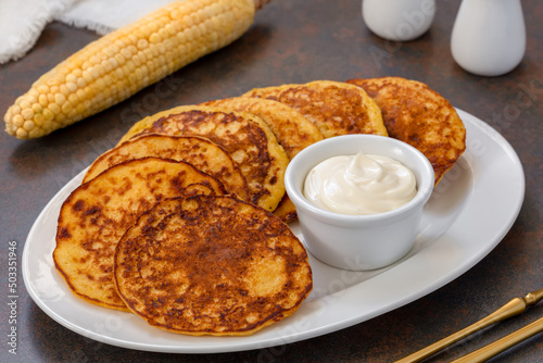 Chorreadas. Corn pancakes made from ground fresh corn served on a plate with with sour cream. Selective focus, concrete background. Horizontal photo