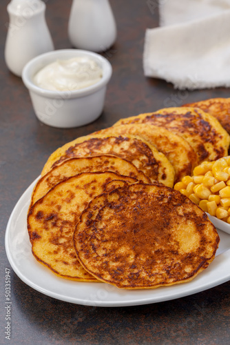 Chorreadas. Corn pancakes made from ground corn served on a plate with with sour cream. Selective focus, concrete background. Vertical. photo
