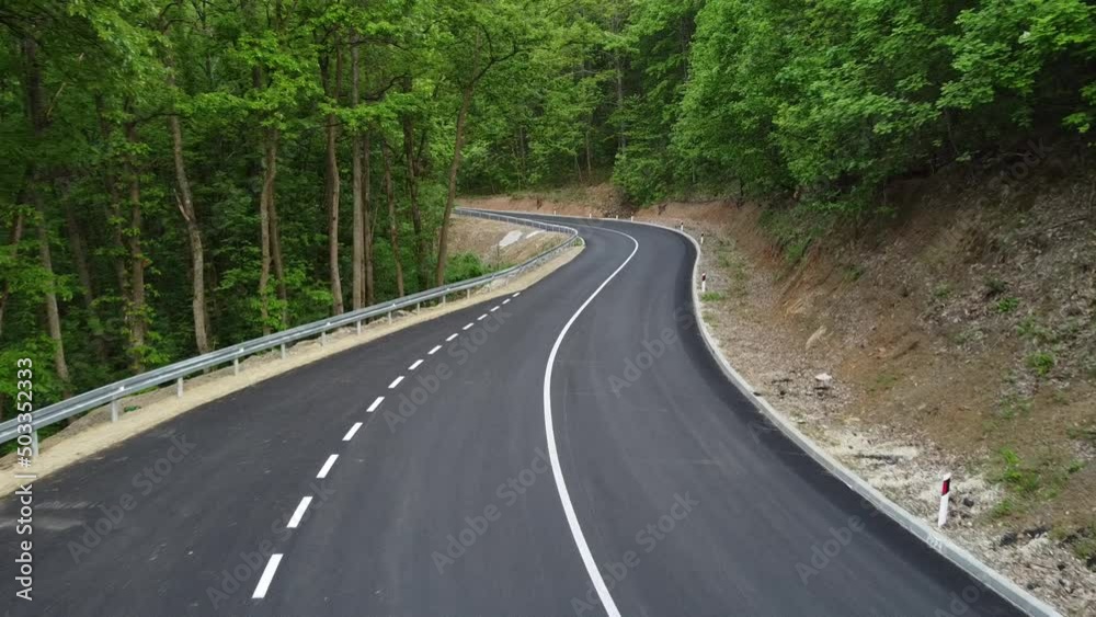 Aerial shot of a winding road passing through a dense green forest Aerial shot of a winding road passing through a dense green forest