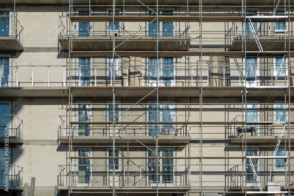 Close up of building uder construction on a sunny day. Building facade and scaffoldings. Close up of building uder construction on a sunny day. Building facade and scaffoldings.