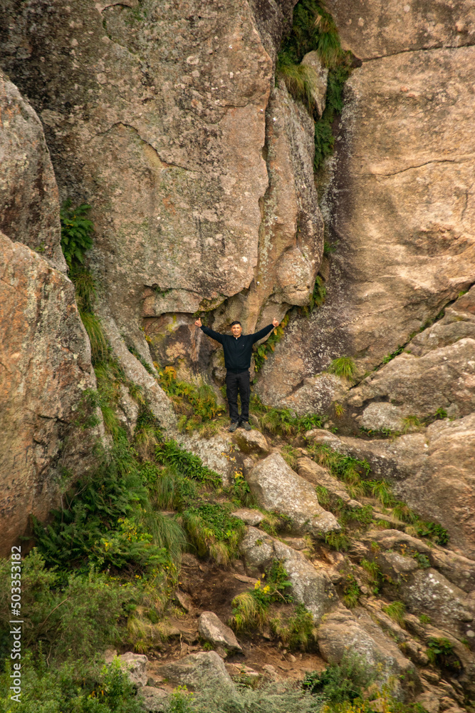 man at the base of a mountain with a huge rock behind him man at the base of a mountain with a huge rock behind him