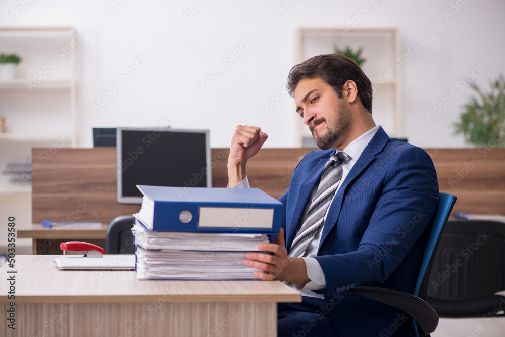Young male employee and too much work in the office Young male employee and too much work in the office