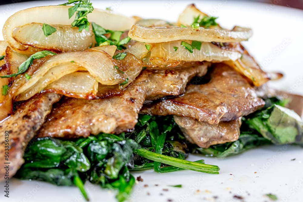 Grilled Liver with Onions closeup in the bowl served with bread on the table. Grilled Liver with Onions closeup in the bowl served with bread on the table.