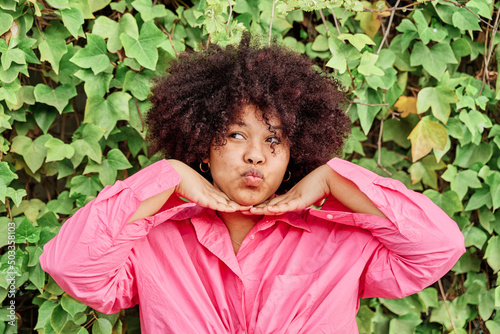Canvas Print african american woman with curly hair posing to camera on background of plants