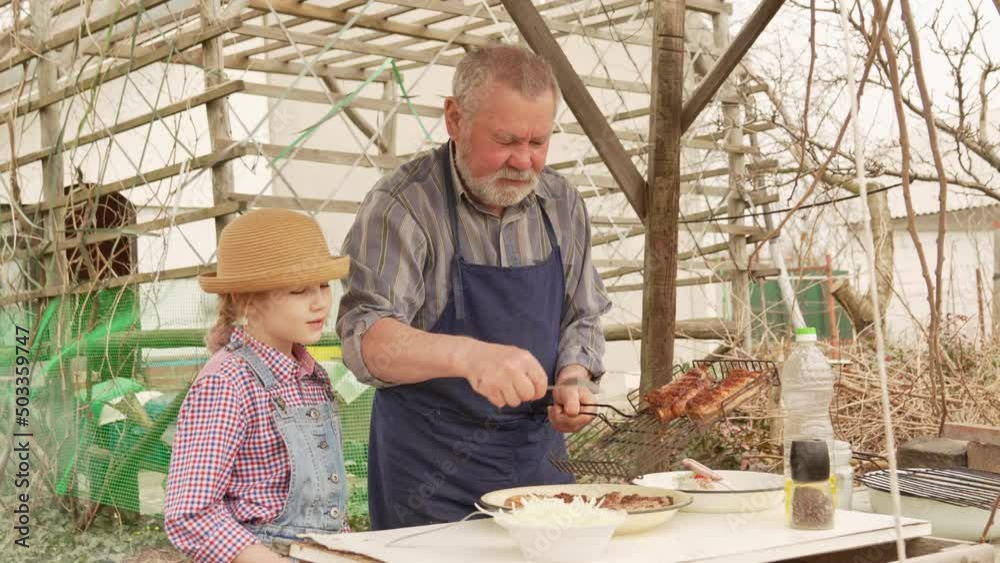 grandfather and granddaughter remove grilled meat, kebab from the grill grate