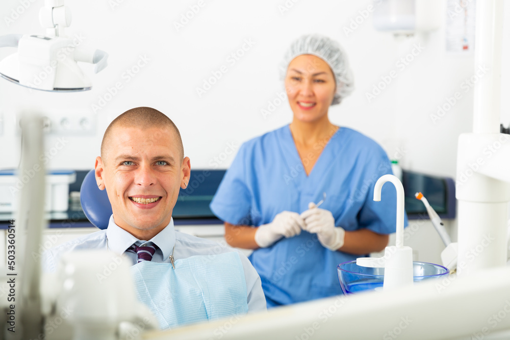 Obraz premium Closeup of happy man sitting in dental chair after teeth cure at stomatology clinic office
