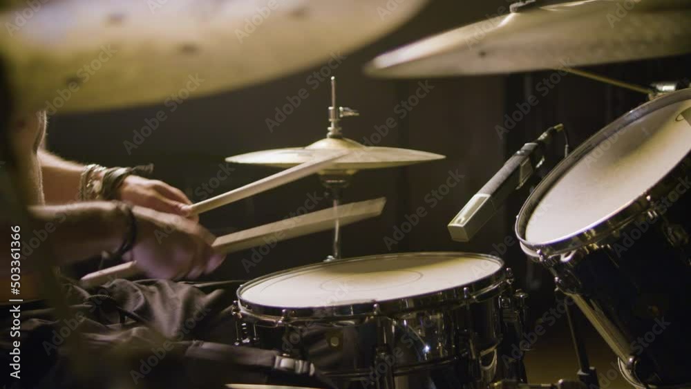 Young male drummer playing drums at music studio while rehearsing alone. Musician performing on percussion instruments. High angle shot. Music, musical instruments concept