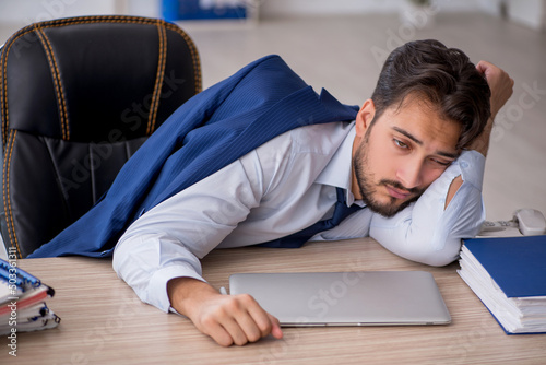 Young male employee extremely tired in the office