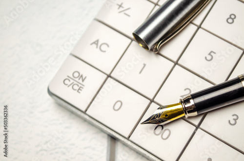 Calculator, pen and eyeglasses on wooden table