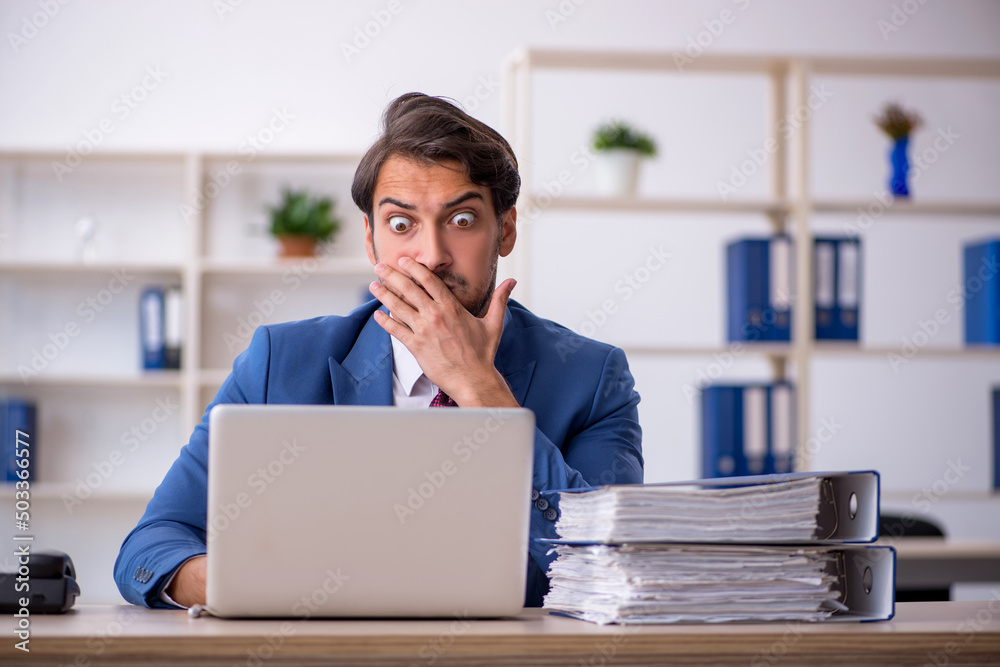 Young male employee and too much work in the office Young male employee and too much work in the office