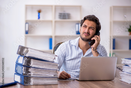 Young male employee unhappy with excessive work in the office