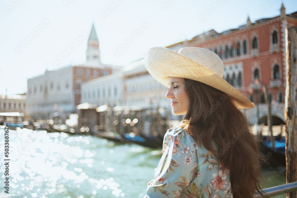 relaxed elegant solo tourist woman in floral dress with hat
