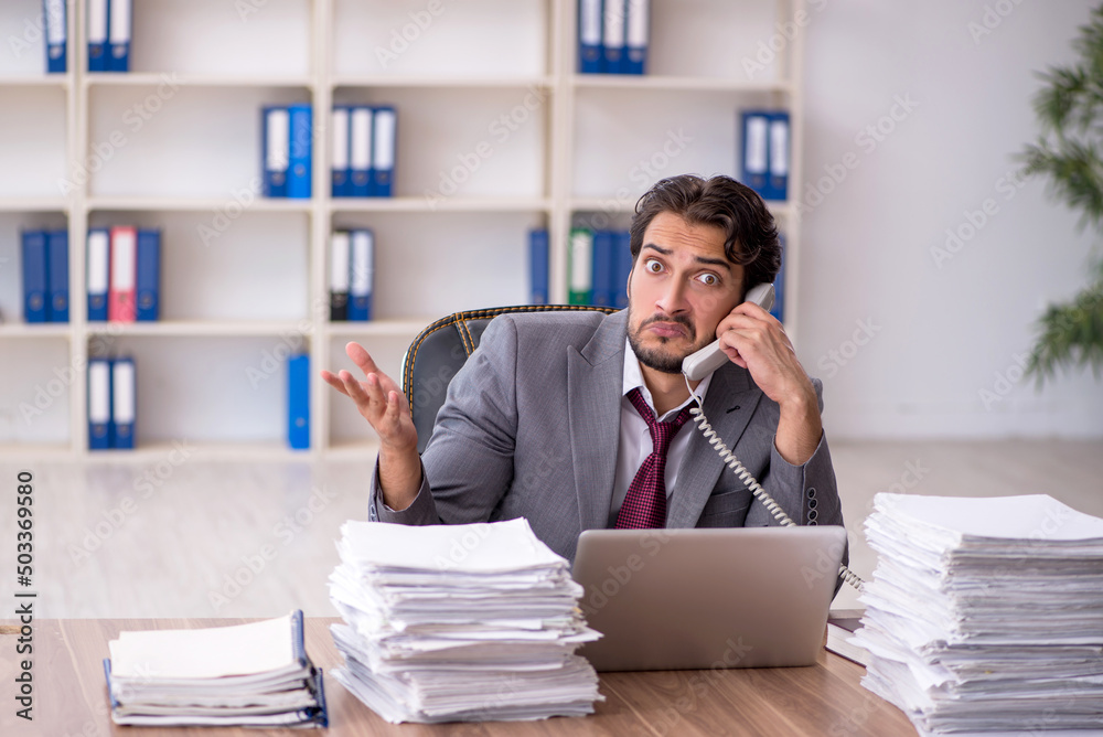 Young male employee and too much work in the office Young male employee and too much work in the office