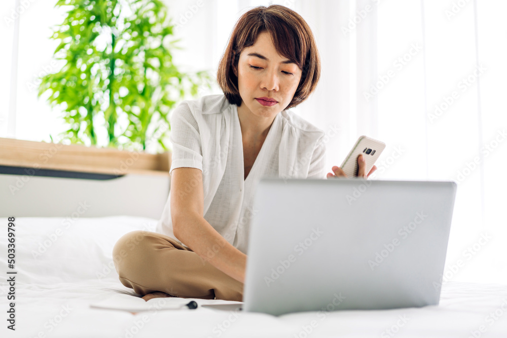 Young smiling happy beautiful asian woman relaxing using laptop computer on sofa at home.Young creative girl working and typing on keyboard.work from home concept Young smiling happy beautiful asian woman relaxing using laptop computer on sofa at home.Young creative girl working and typing on keyboard.work from home concept
