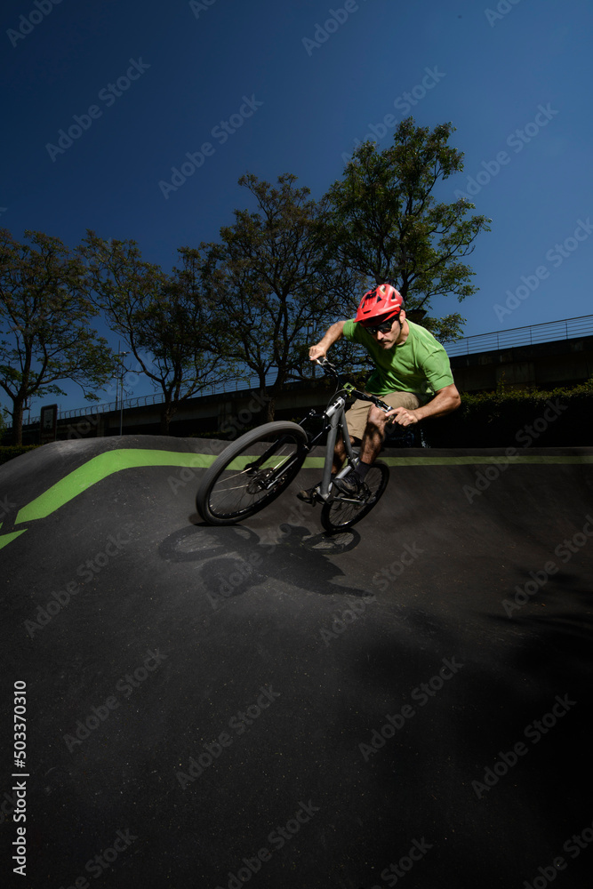 Obraz premium rider with a dirt bike training on a pump track. the rider is riding up a bank.