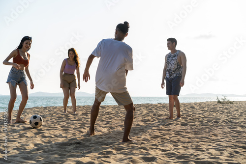 Group of Asian young man and woman play soccer on the beach together.  photo