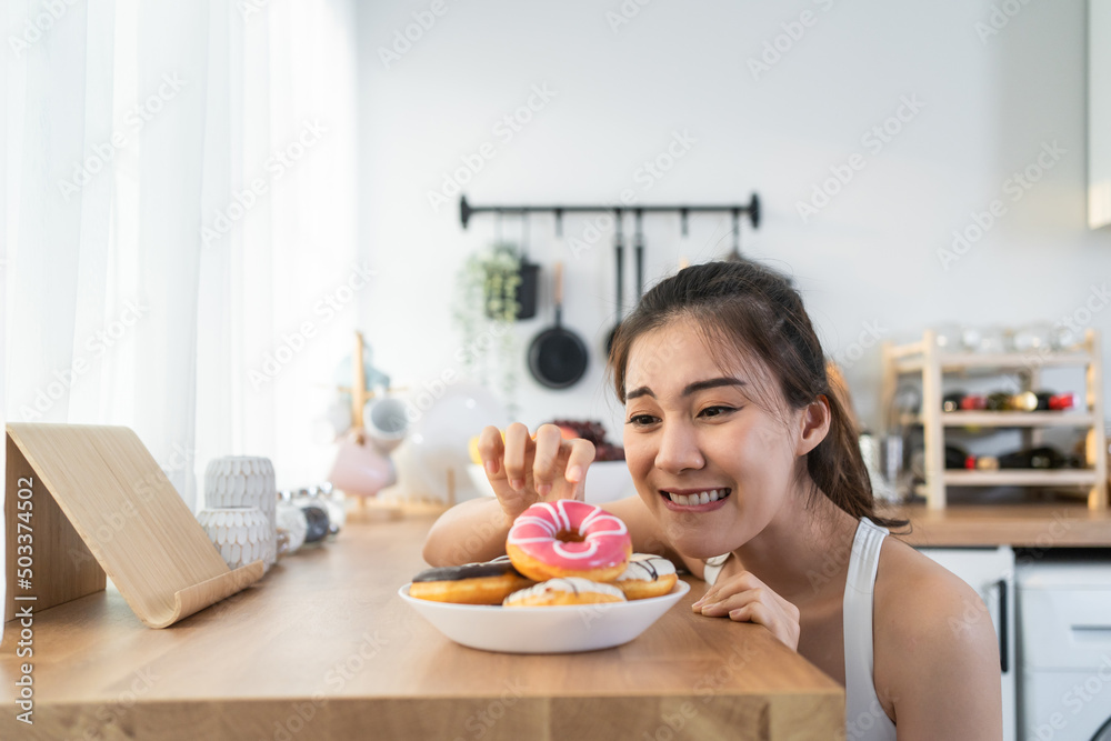 Asian beautiful young girl hungry and want to eat donut in kitchen. 