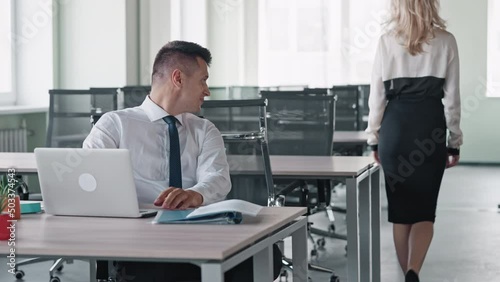 manager sitting at the workplace in office woman passes by table flirt or harassment at work concept