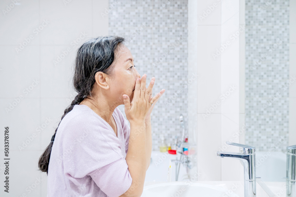 Senior woman doing treatment face skin in bathroom Senior woman doing treatment face skin in bathroom