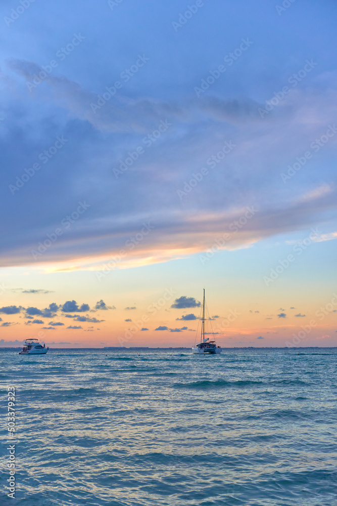 sailing boat in the coast of isla mujeres Cancun at the sunset with a sky at the golden hour. mexican beaches of the riviera maya