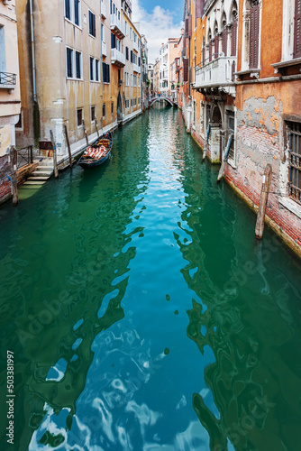Narrow canal with gondola in Venice, Italy. © Sergey