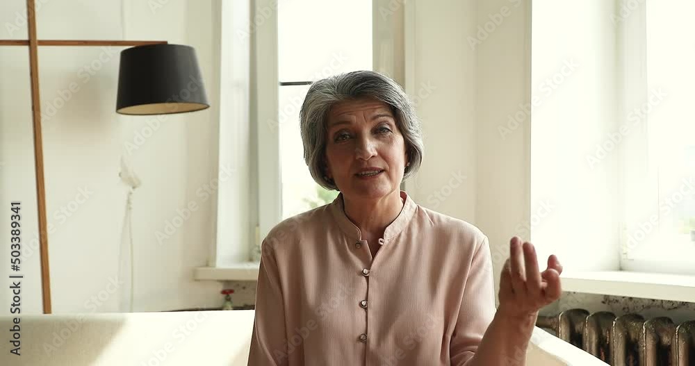 Head shot webcam portrait elegant old age female teacher sit on sofa before web camera broadcast live video class from home. Mature woman tutor coach explain new lesson to students on distant learning Head shot webcam portrait elegant old age female teacher sit on sofa before web camera broadcast live video class from home. Mature woman tutor coach explain new lesson to students on distant learning
