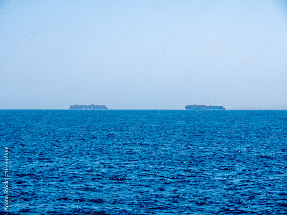 Two large cargo ships carrying containers by sea.